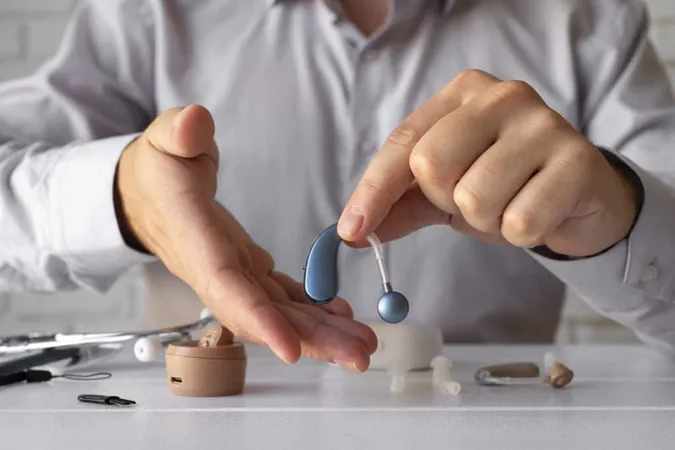 Front View Man Holding Hearing Aids X - American Board of Audiology study guide