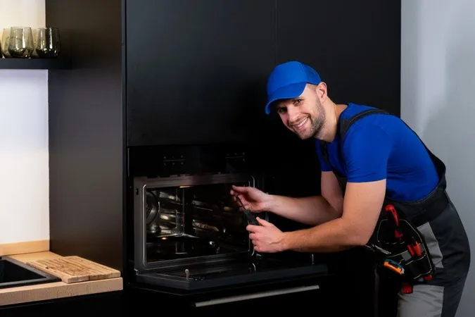 Repairman Worker Uniform Inspects Oven With Screwdriver Kitchen Concept Rep X - Appliance Service Fundamentals Certification study guide