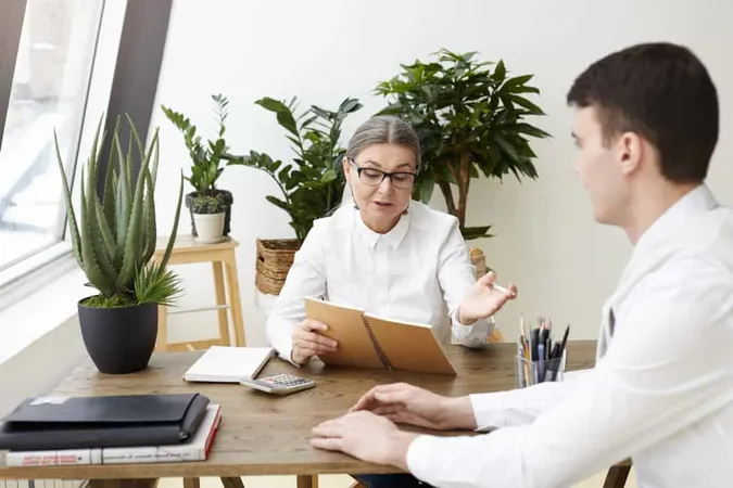 Confident Attractive Woman Ceo Her Fifties Holding Copybook While Posing Questions About Job Qualification Experience Skills Interview With Brunette Male Applicant Fi X - Behavioral Health Professional Certification study guide