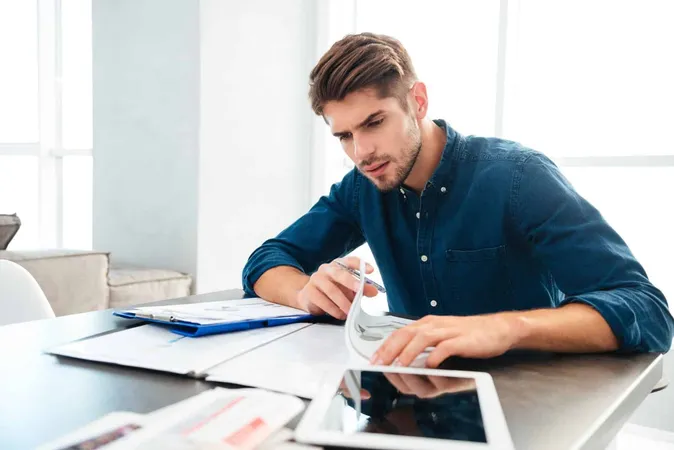 Busy Young Man Home Analyzing His Home Finances While Sitting Near Tablet - California Department of Motor Vehicle study guide