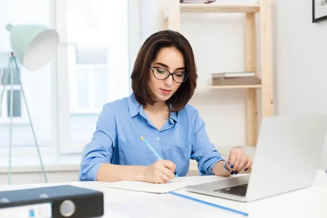 Pretty Brunette Girl Is Working Table Office She Wears Blue Shirt Black Glasses She Is Writing Seriously X - Certified Accounting Technician study guide