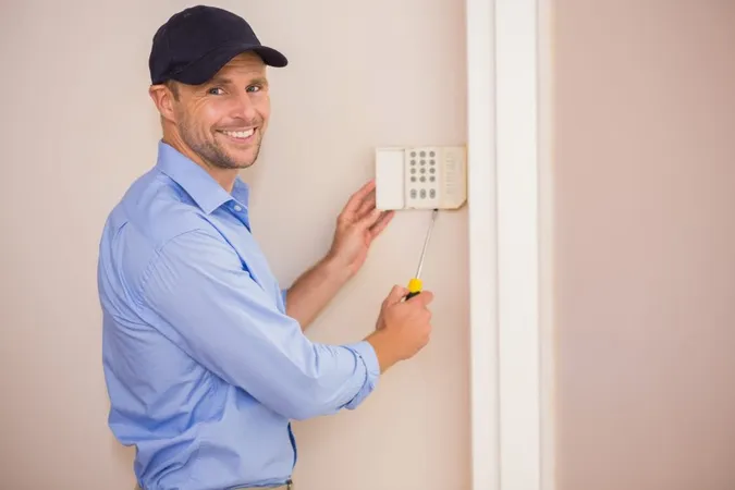 Smiling Handyman Fixing Alarm System X - Certified Alarm Technician Level I study guide