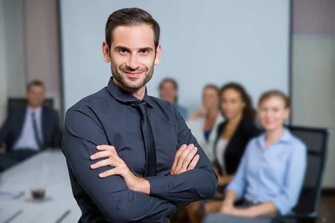 Man Smiling With Suit Sitting Table With Colleagues X - Certified Business Coach study guide