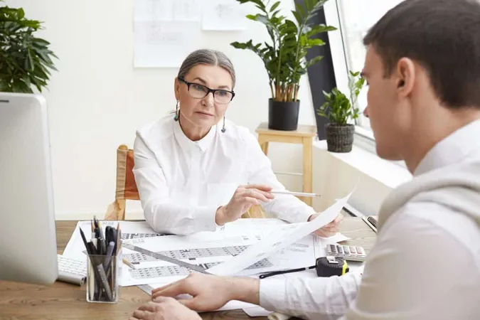 Serious Middle Aged Female Senior Engineer Eyeglasses Holding Pencil Piece Paper Looking Young Brunette Employee With Strict Questioning Expression Pointing Mistakes Drawings X - Certified Claims Adjuster study guide