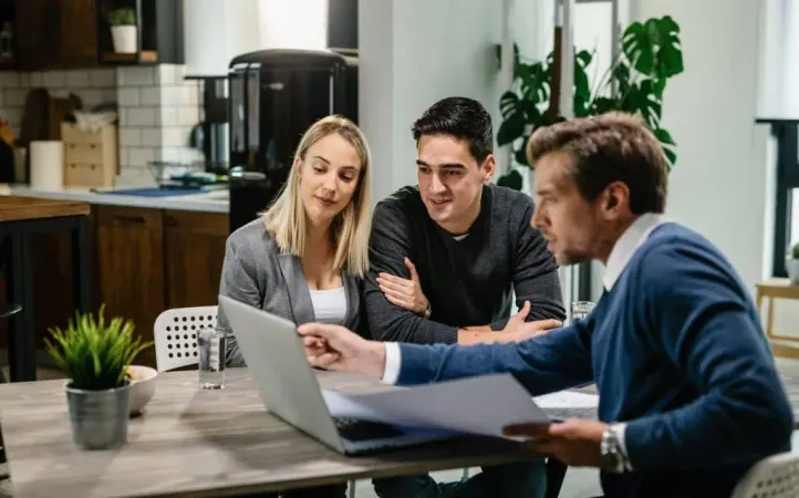 Young Couple Real Estate Agent Using Laptop While Going Through Housing Plan Meeting X - Certified Estate Advisor study guide
