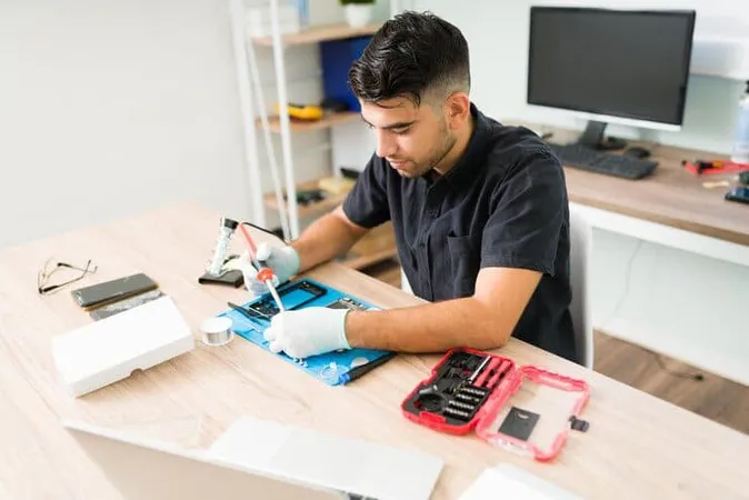 Attractive Young Man Technician Using Soldering Iron While Trying Fix Hardware Damaged Smartphone - Certified Mobile Tech study guide