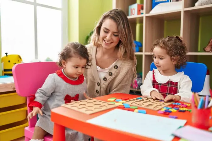 Teacher With Girls Playing With Maths Puzzle Game Sitting Table Kindergarten X - Certified Professional Nanny study guide