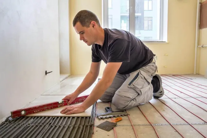 Young Worker Tiler Installing Ceramic Tiles Using Lever Cement Floor With Heating Red Electrical Cable Wire System Home Improvement Renovation Construction Comfortable Warm Home Concept X - Certified Tile Installer study guide