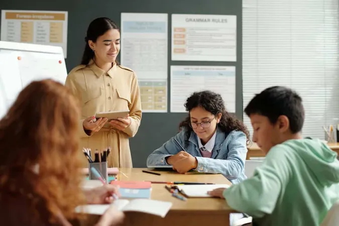 Young Smiling Teacher English Language Using Tablet While Checking Notes X - Department of Elementary and Secondary Education Certification study guide