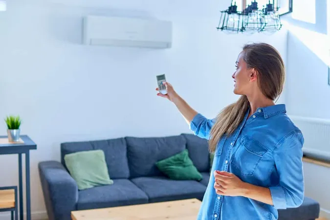 Young Cute Casual Woman Using Air Conditioner Adjusting Comfortable Temperature With Remote Control Apartment X - Home Energy Rater Certification study guide