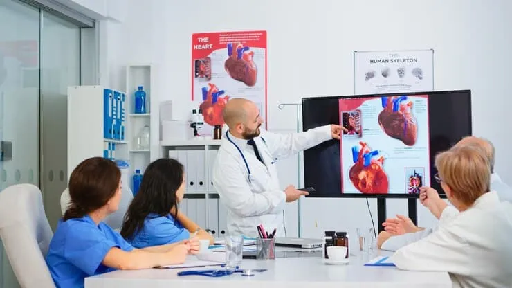 Experienced Man Doctor Analysing Heart Issues Together With Cvalified Colleagues Meeting Room Pointing Monitor Doctors Discussing Diagnosis About Treatment Patients - National Board of Echocardiography study guide