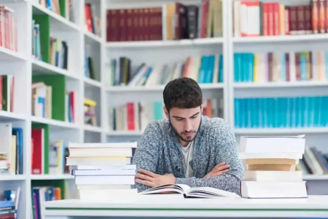 Portrait Happy Student While Reading Book School Library Study Lessons Exam Hard Worker Persistance Concept - New Jersey Graduation Proficiency Assessment study guide