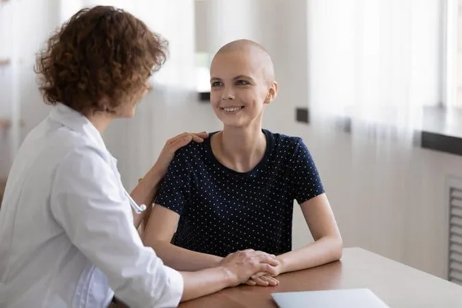 Hopeful Young Sick Woman Sit Desk Doctor Office Listen Attending Physician Believe Trust Her Happy Grateful Female Patient Talk Oncologist Meeting Feel Cancer Free Excited Rec - Oncology Chemotherapy Certification study guide