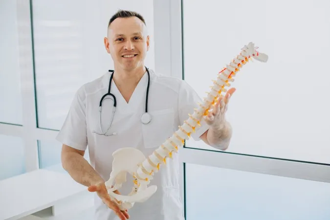 Vertebrae Physiotherapist Holding Artificial Spine X - Orthopedic Certified Specialist study guide