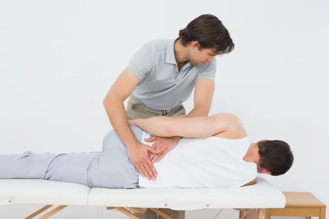 Male Physiotherapist Examining Mans Back X - Orthopedic Massage Certification study guide