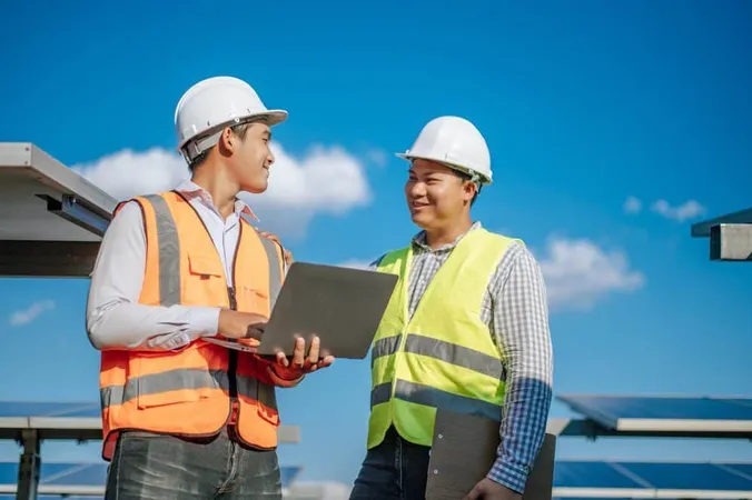 Young Asian Technician Man Colleague Safety Uniform Checking Operation Sun Photovoltaic Solar Panel Use Laptop Computer While Working Solar Farm - Procore Superintendent Certification study guide