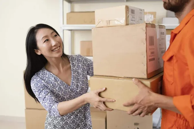 Smiling Young Woman Handing Delivery Boxes Courier X - Relocation Specialist Certification study guide