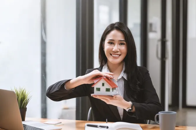 Young Asian Businesswoman Real Estate Agent Holding House Samples Mortgage Looking Camera X - Wisconsin Real Estate License study guide